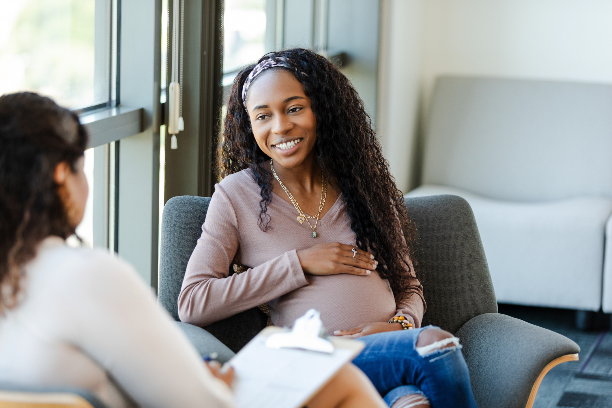 Pregnant person talking to other person with clipboard